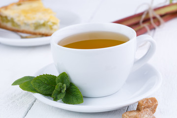 Mint tea with slice of rhubarb pie on wooden table.