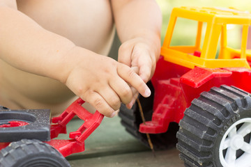 hand of a young child holding a toy red tractor