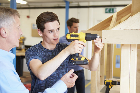 Teacher Helping College Student Studying Carpentry