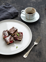Cheesecake brownie squares with raspberries and coffee on white