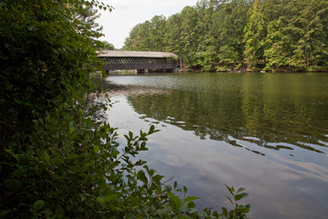 Fototapeta na wymiar Wooden covered bridge over a still lake