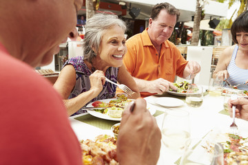 Group Of Senior Friends Enjoying Meal In Outdoor Restaurant