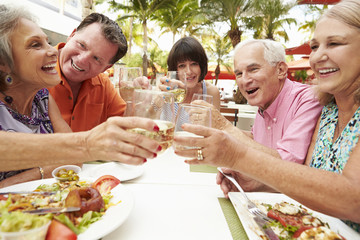 Group Of Senior Friends Enjoying Meal In Outdoor Restaurant