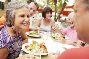 Group Of Senior Friends Enjoying Meal In Outdoor Restaurant