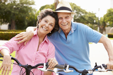 Senior Hispanic Couple Riding Bikes In Park