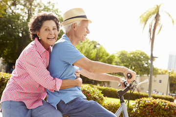 Senior Hispanic Couple Riding Bikes In Park