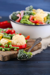Frozen vegetables on cutting board, on napkin, on wooden table background