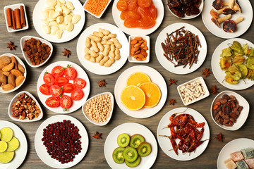 Different products on saucers on wooden table, top view