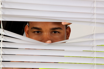 Black man peeking through blinds