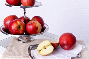 Tasty ripe apples on serving tray on brick wall background