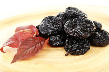 Pile of prunes with leaves on wooden background
