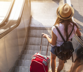 Young girl with suitcase down the escalator.