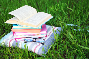 Books and glasses on pillow on grass close-up