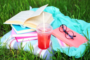 Books, glasses and drink on grass close-up