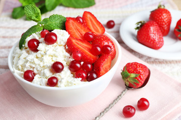 Bowl of cottage cheese with strawberry and cranberry on table, closeup