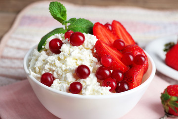 Bowl of cottage cheese with strawberry and cranberry on table, closeup