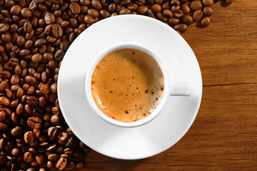 Cup of fresh coffee with beans on table, top view