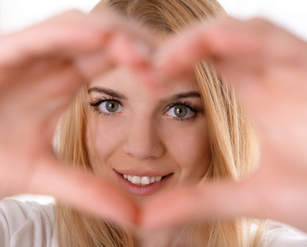 Smiling Attractive Young Woman Makes Heart Using Fingers