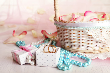 Wedding basket with roses petals on table, on light background