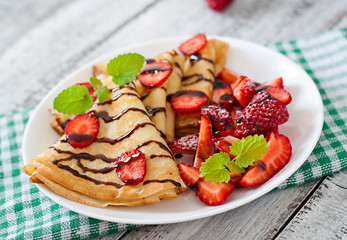 Pancakes with strawberries and chocolate decorated with mint leaf