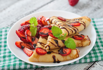 Pancakes with strawberries and chocolate decorated with mint leaf