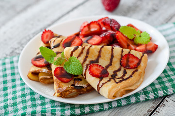 Pancakes with strawberries and chocolate decorated with mint leaf