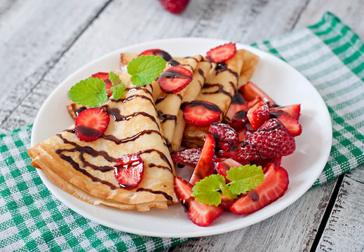 Pancakes with strawberries and chocolate decorated with mint leaf