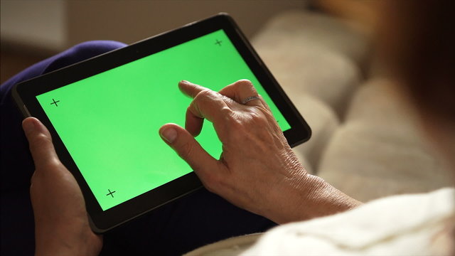 Elderly woman using a tablet PC with green screen