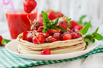 Pancakes with berries and strawberry smoothie in a rustic style