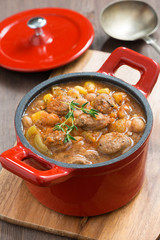 delicious vegetable stew with sausages in a red pan 