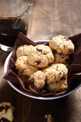 Many cookies with cranberries in a bowl and coffee