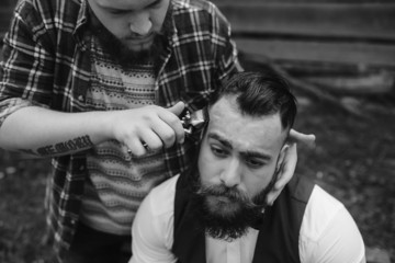 barber shaves a bearded man Outdoors