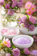 Fototapeta na wymiar spa with pink herbal salt and wild rose flowers clover