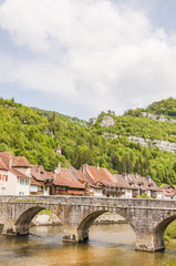 Fototapeta na wymiar Saint-Ursanne, St. Ursanne, Altstadt, Stadt, Steinbrücke, Bogenbrücke, Frühling, Jurakette, Schweiz