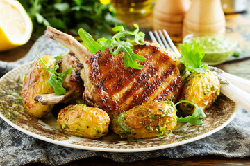 Grilled pork chop on the bone with spicy potatoes. Selective focus.