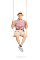 Joyful senior man sitting on a swing and posing