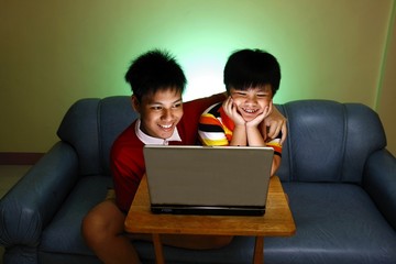 Two Young boys using a laptop computer and smiling