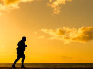 Silhouette fat man running at sunset