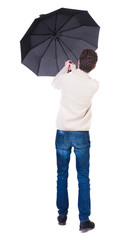 Back view of man in jeans under an umbrella. Standing young guy.