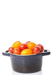 Yellow and red grape tomato in a blue pot over white background