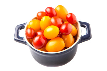 Yellow and red grape tomato in a blue pot over white background
