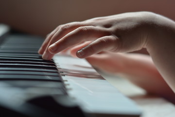 Fototapeta na wymiar Детские руки на клавишах пианино при дневном свете