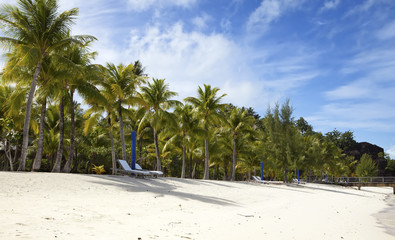 Umbrella and chaise lounges on a beach.
