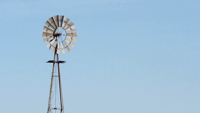 Close-up to a rotating windmill for pumping water over blue sky