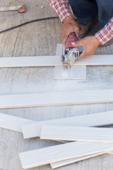 carpenter hands using electric saw on wood at construction site
