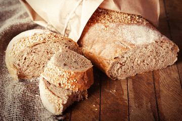 Fresh baked bread wrapped in paper, on wooden background