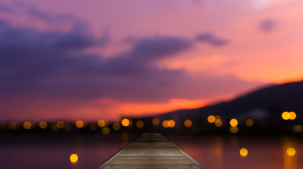 Colorful bokeh of city from the sea in night time and wooden
