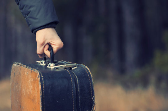 Ancient suitcase in a hand on rusty grunge a background.  Old suitcases.