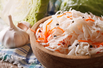 homemade sauerkraut with carrot in a wooden plate  - obrazy, fototapety, plakaty