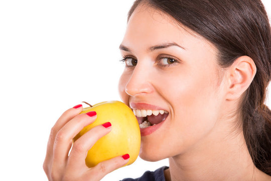 young woman eating apple, looking at camera, white background